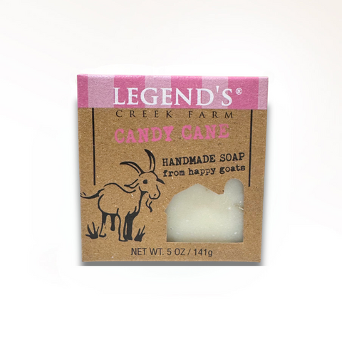 A bar of goat milk soap with a candy cane design, packaged in a brown box with a label that reads 'Legend's Creek Farm Candy Cane Soap, Handmade Gats' and indicates the net weight of 6 oz. (175g).