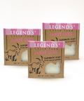 Three packages of Legend's Creek Farm Candy Cane Handmade Goat Milk Soap, with the scent of candy canes. The packaging is primarily pink and beige, with an illustration of a goat and candy cane motifs.