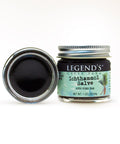 A jar of Ichthammol Pine Tar Drawing Salve with its lid off, showing the dark salve inside. The label on the jar reads ' Legends Creek Farm Ichthammol Salve with Pine Tar'.